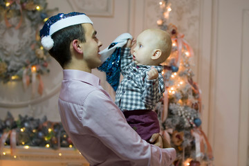 Father and son on New Year's Eve. Baby on the hands of dad in Santa Claus hats