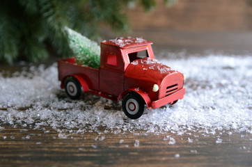 Red car carrying a Christmas fir tree on the snow background. Concept for Merry Christmas  and Winter holidays.