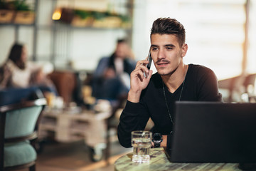Young man with mobile phone in cafe