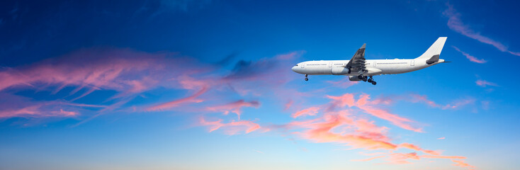 Naklejka na ściany i meble Airplane flying above dramatic clouds during sunset