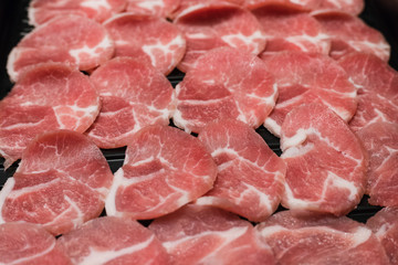 The close up of slide raw pork on a black plate.
