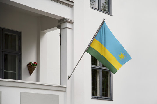 Rwanda Flag Hanging On A Pole In Front Of The House. National Flag Waving On A Home Displaying On A Pole On A Front Door Of A Building And Raised At A Full Staff.