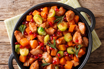 Delicious chicken cooked with vegetables and rosemary in pomegranate sauce close-up in a pan. horizontal top view