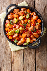 Freshly cooked chicken with vegetables in pomegranate sauce close-up in a frying pan. Vertical top view