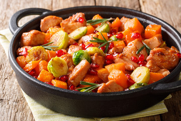 Delicious chicken cooked with vegetables and rosemary in pomegranate sauce close-up in a pan. horizontal