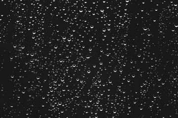 Dirty window glass with drops of rain. Atmospheric monochrome dark background with raindrops. Droplets and stains close up. Detailed transparent texture in macro with copy space. Rainy weather.