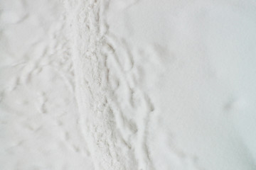 Traces of shoes on clean white snow. Track of boots on snowdrift. Textured winter background of snowy footpath. Snow covered road with copy space. Abstract minimalist snowy weather texture.