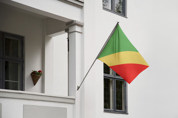 Congo flag hanging on a pole in front of the house. National flag waving on a home displaying on a pole on a front door of a building and raised at a full staff.