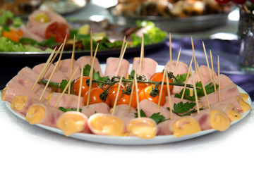 Close up of small canapes arranged on a plate over light background - selective focus