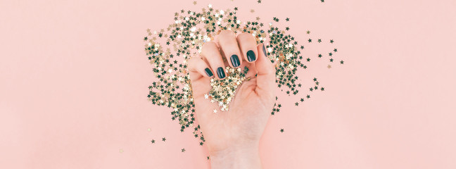 Woman hands covered golden stars confetti on pink