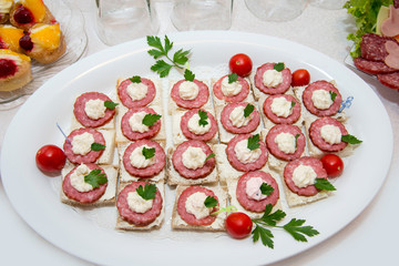 Close up of small canapes arranged on a plate over light background - selective focus