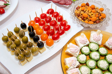 Close up of small canapes arranged on a plate over light background - selective focus