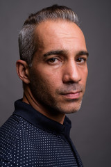 Face of handsome Persian man with gray hair against gray background