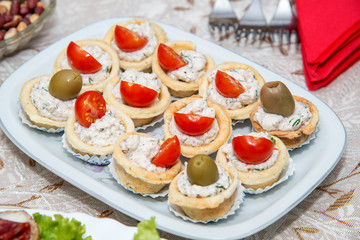 Close up of small canapes arranged on a plate over light background - selective focus