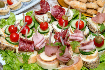 Close up of small canapes arranged on a plate over light background - selective focus