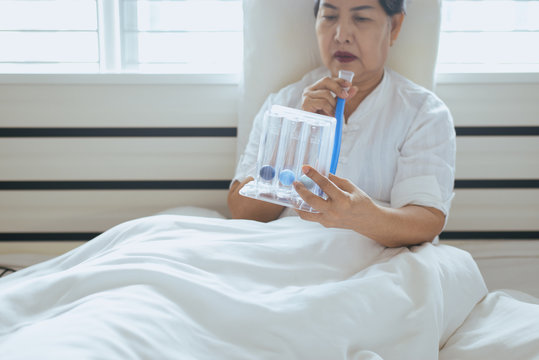 Patient elderly people woman using incentive spirometer or three balls for stimulate lung in bedroom