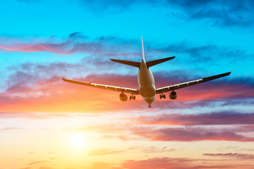 Airplane flying above dramatic clouds during sunset
