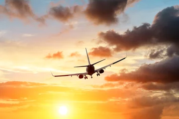 Poster Kommerzielles Flugzeug, das während des Sonnenuntergangs über dramatischen Wolken fliegt © ABCDstock