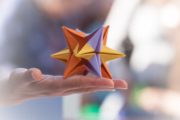 Hand holding and showing a colorful modular origami star. Lightness concept.