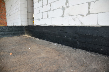 Foundation bitumen waterproofing. Building house construction with waterproofing spray-on tar....