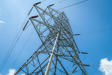 Power transmission tower against blue sky with some low clouds in Kashmir, India shot from a low angle