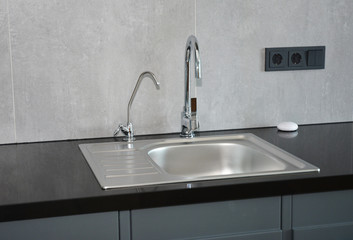 Modern kitchen with faucet and metal kitchen sink and outlets.