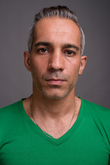 Handsome Persian man with gray hair wearing green t-shirt