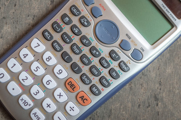 Top view of a white scientific calculator kept on a grey textured backgrround