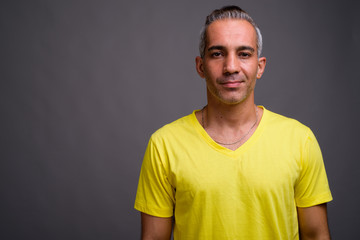 Handsome Persian man with gray hair wearing yellow t-shirt