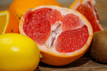 Naklejka na ściany i meble Various raw citrus fruit on wooden table. Close-up of lemon, orange, grapefruit and kiwi.