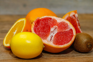 Various raw citrus fruit on wooden table. Close-up of lemon, orange, grapefruit and kiwi.
