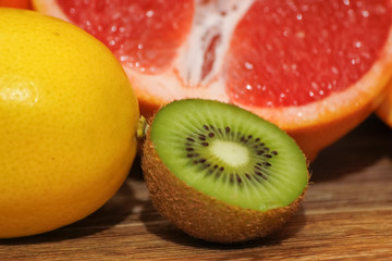 Obraz na płótnie Canvas Various raw citrus fruit on wooden table. Close-up of lemon, orange, grapefruit and kiwi.