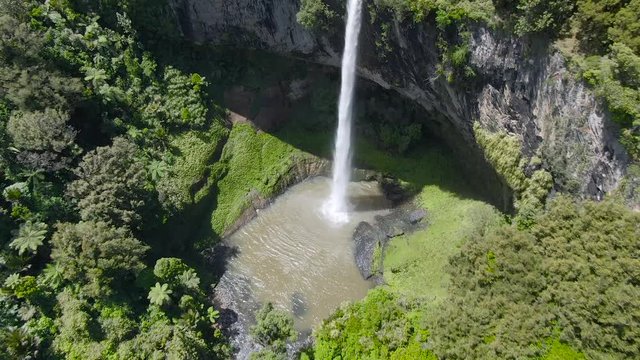 A fly away and tilt yup camera movement of a footage revealing the beautiful surroundings around a stunning 55m waterfall in the middle of subtropical forest. 4k Video quality