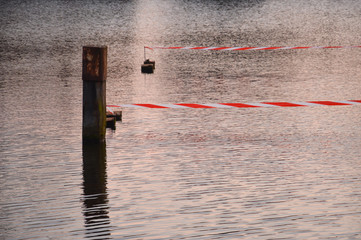 sunlight glinstering in the water with a bollard or dolphin in