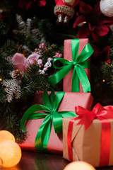 Gifts lie under the tree with a glowing gerland on a dark wooden floor