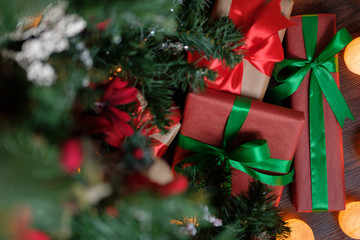 Gifts lie under the tree with a glowing gerland on a dark wooden floor