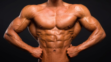 Strong Athletic Man Fitness Model Torso showing six pack abs on dark background.