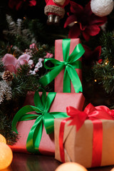 Gifts lie under the tree with a glowing gerland on a dark wooden floor