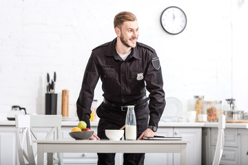 handsome police officer standing next to table at kitchen