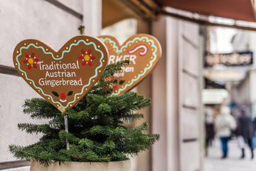 Vienna, Austria - December 30, 2017. Gingerbread bakery signs with traditional cookies in heart shape and text. Close view of plate with ornament and christmas tree branches.