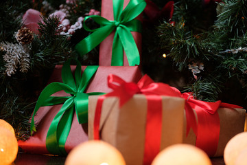 Gifts lie under the tree with a glowing gerland on a dark wooden floor
