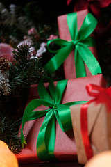 Gifts lie under the tree with a glowing gerland on a dark wooden floor