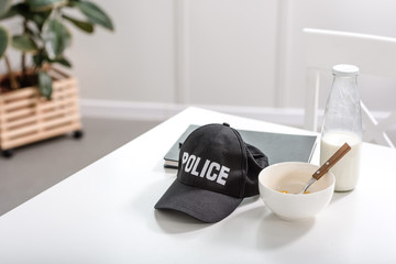 notebook, police cap and bowl with breakfast on white table