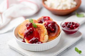 Cottage cheese fritters or syrniki with fruit jam on white plate. Selective focus. Tasty breakfast