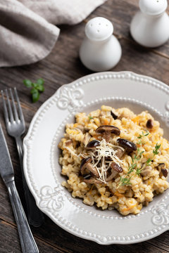 Barley mushroom risotto on plate. Traditional italian cuisine meal, vegetarian risotto with pearl barley and mushrooms on rustic wooden table, top view