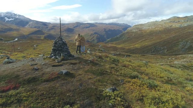 Hiker man and woman standing on the top of the mountain loing epic view