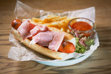 plate with hot dog with sausage and ham, tomato sauce ketchup and french fried on the table 