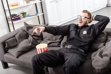 policeman in 3d glasses sitting on couch and  watching movie