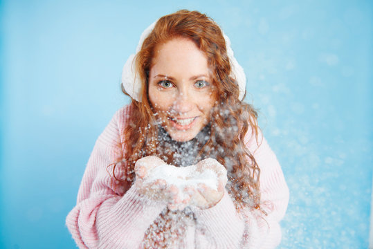 Portrait Of Smiling Woman Blowing Fake Snow At Studio Shot