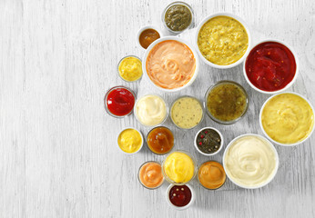 Different tasty sauces in bowls on white wooden table